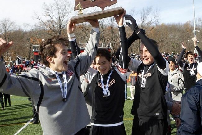 Wayland's Scott Hojilo (5) and Alec Foster (right), shown hoisting the state championship trophy last fall with teammate Andres Pascual Leone (left), are mentoring younger players at the Champion Soccer School this summer. WICKED LOCAL STAFF FILE PHOTO/MARSHALL WOLFF